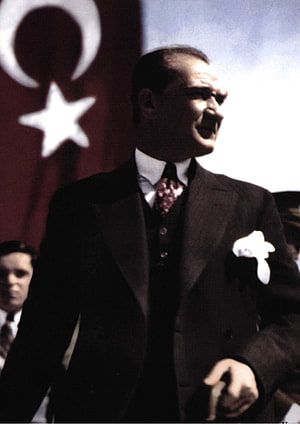 Mustafa Kemal Ataturk in a formal suit standing before the Turkish flag HD phone wallpaper