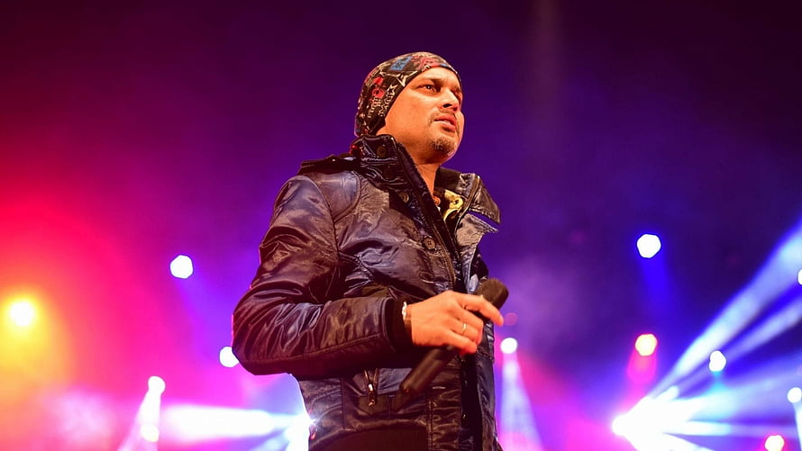 Zubeen Garg performing live on stage with microphone under vibrant concert lighting HD wallpaper