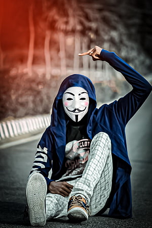 Person in Guy Fawkes Mask and Blue Hoodie Sitting on Asphalt Road HD phone wallpaper