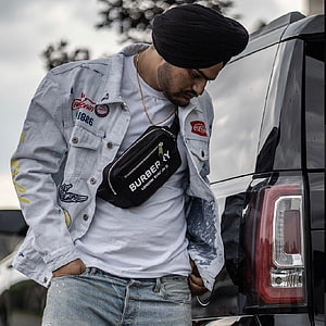Sidhu Moose Wala in distressed denim jacket and black turban beside a black SUV HD phone wallpaper