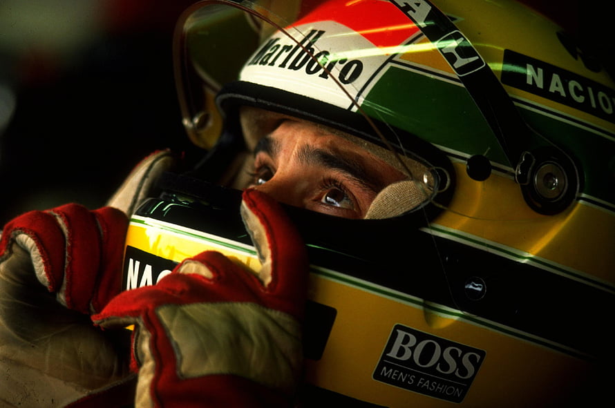 Ayrton Senna in his iconic yellow and green racing helmet with Marlboro and Boss sponsor logos HD wallpaper