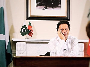 Imran Khan Seated at Desk in Formal White Attire with Pakistan Flag HD wallpaper
