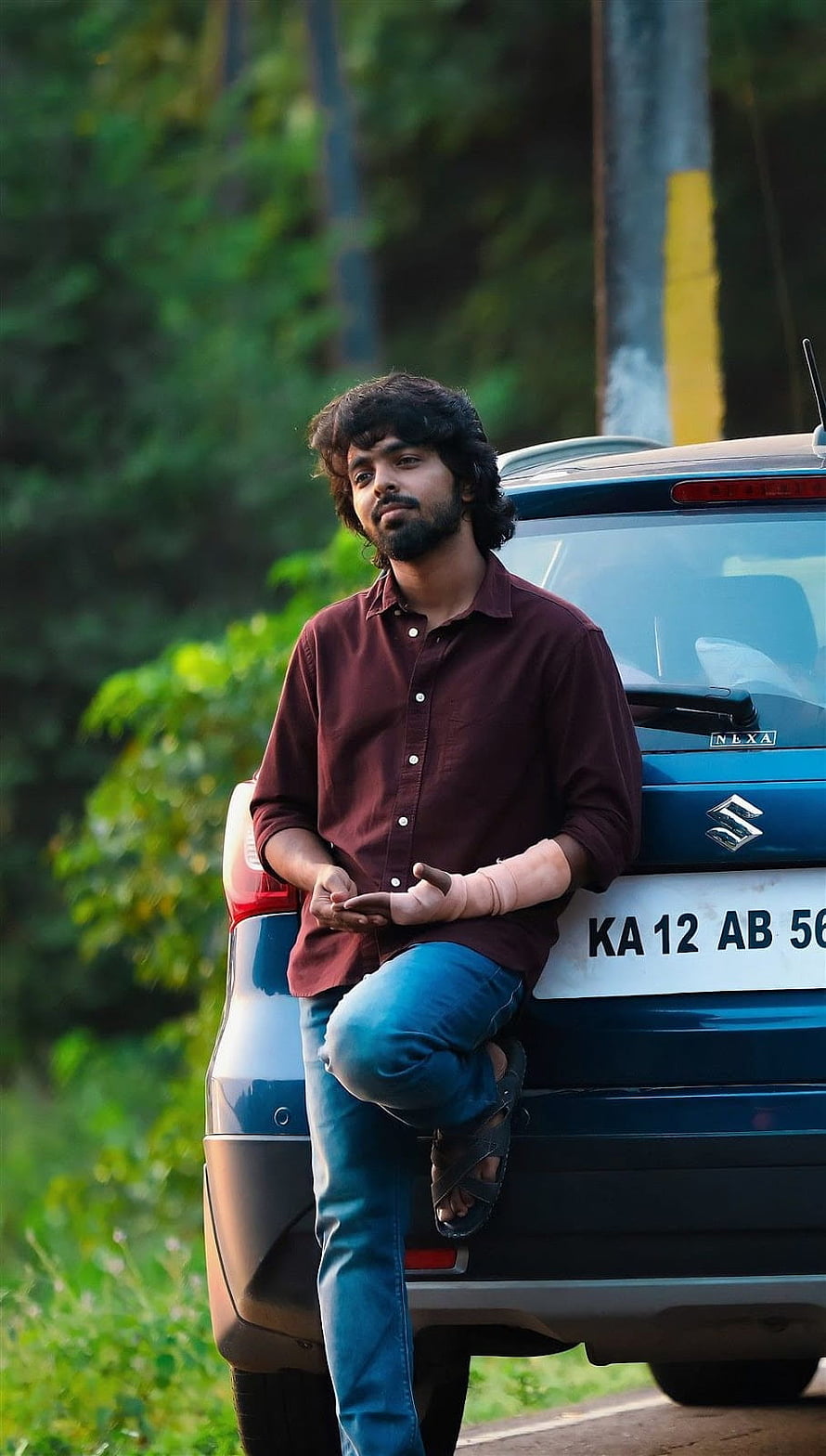 GV Prakash Leaning Against Blue Maruti SX4 in Lush Green Forest Setting HD phone wallpaper